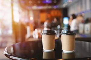 Nehmen Sie zwei Kaffeetassen mit, leerer, leerer Kopierraum für Ihren Designtext oder Ihr Markenbanner auf dem Tisch im Café mit Licht