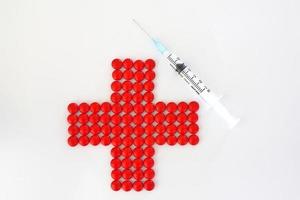 Rotes Kreuz mit roten Pillen und Spritze foto