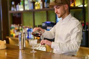 männlicher barkeeper, der alkohol in shaker gießt foto