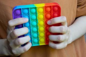 Hände halten ein berührungsempfindliches Zappelspielzeug. blaue und orange lustige interaktive Anti-Stress-Silikonspielzeuge foto