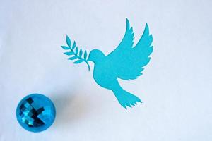 eine taubenschablone mit einem zweig, ausgeschnitten aus weißem papier auf blauem hintergrund für den weltfriedenstag. Weltwissenschaftstag für Frieden und Entwicklung foto
