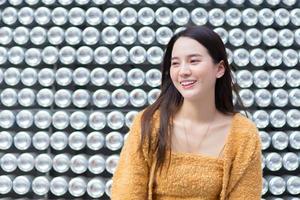 schöne asiatische frau mit schwarzen langen haaren im gelben mantel lächelt hübsch. foto