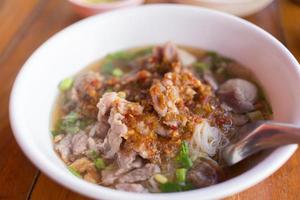 Reisnudeln Reisnudeln mit Schweinefleisch Suppe enthält Fleischbällchen, Fleisch und eingelegtes Chili auf holzigen Hintergrund gegossen. foto