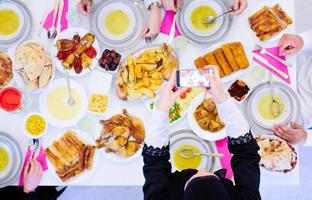 muslimische familie beim iftar-abendessen, das fotos mit dem handy macht