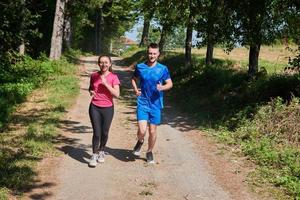 Paar genießt einen gesunden Lebensstil beim Joggen auf einer Landstraße foto