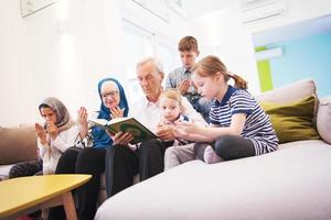 moderne muslimische großeltern mit enkelkindern, die den koran lesen foto