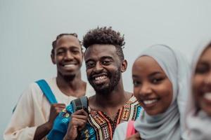 Foto einer Gruppe glücklicher afrikanischer Studenten, die miteinander reden und sich treffen, um an Hausaufgaben zu arbeiten, Mädchen, die traditionellen sudanesischen muslimischen Hijab tragen