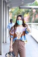 schöne asiatin, die in der stadt spazieren geht, trägt bunte pullover, lange haare und medizinische masken in einem neuen normalen, umweltverschmutzungs-pm2.5- und gesundheitskonzept. foto
