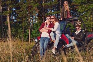 Gruppe junger glücklicher Menschen, die einen schönen sonnigen Tag genießen, während sie ein Offroad-Buggy-Auto fahren foto
