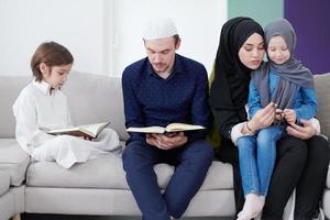 muslimische familie, die koran liest und zu hause betet foto