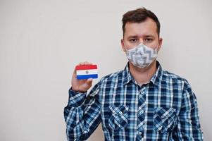 Mann im karierten Hemd zeigt Paraguay-Flaggenkarte in der Hand, trägt Schutzmaske isoliert auf weißem Hintergrund. Coronavirus-Konzept der amerikanischen Länder. foto