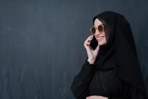 junge muslimische geschäftsfrau in traditioneller kleidung oder abaya mit smartphone foto