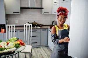 afroamerikanerfrau zu hause küche offener kühlschrank. foto