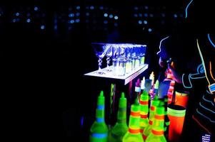 Professioneller Barkeeper und LED-Lichtshow. Silhouette eines modernen Barkeepers, der in der Nachtcocktailbar ein Getränk schüttelt. foto