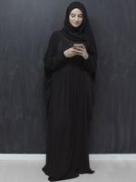 junge muslimische geschäftsfrau in traditioneller kleidung oder abaya mit smartphone foto