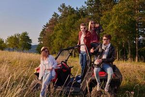 Gruppe junger glücklicher Menschen, die einen schönen sonnigen Tag genießen, während sie ein Offroad-Buggy-Auto fahren foto