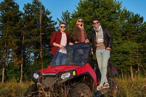 Gruppe junger glücklicher Menschen, die einen schönen sonnigen Tag genießen, während sie ein Offroad-Buggy-Auto fahren foto