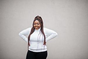 Glamouröse Afroamerikanerin in weißer Rollkragenpullover-Pose auf der Straße. foto