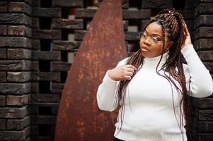 Glamouröse Afroamerikanerin in weißer Rollkragenpullover-Pose auf der Straße. foto