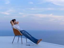 Entspannter junger Mann zu Hause auf dem Balkon foto