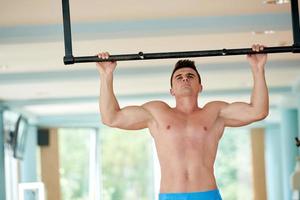 hübscher junger Mann, der im Fitnessstudio trainiert foto