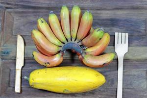 Bündel große Bananenfrüchte und eine große Papaya auf Holzhintergrund foto