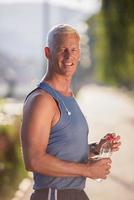 älterer joggender mann, der frisches wasser aus der flasche trinkt foto