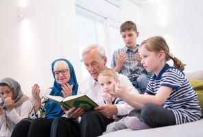 moderne muslimische großeltern mit enkelkindern, die den koran lesen foto