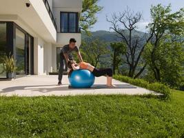 frau und persönlicher trainer, der übung mit pilatesball tut foto