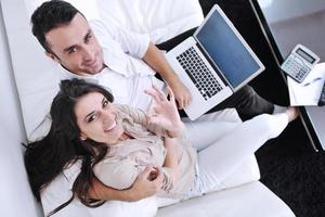 Fröhliches Paar entspannen und arbeiten am Laptop im modernen Zuhause foto