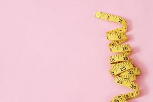 Maßband für übergewichtige Menschen auf einem rosa Hintergrund weicher Fokus foto