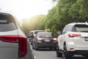 Rückseite des grauen Autos auf der Asphaltstraße in Richtung des Ziels der Reise. Arbeitsweg während der Hauptverkehrszeit. Umgebung verschwommen von anderen Autos in der Stadt. daneben eine Insel mit grünen Bäumen. foto