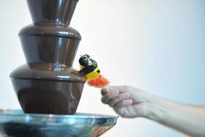 flüssiger Schokoladenbrunnen und frisches Obst am Stiel foto