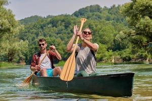 Freunde fahren in einem wilden Fluss Kanu foto