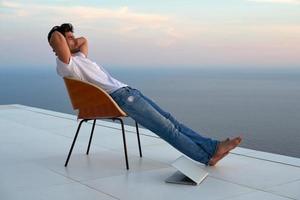 Entspannter junger Mann zu Hause auf dem Balkon foto