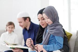 muslimische familie, die koran liest und zu hause betet foto