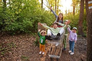 mutter und kinder mit wagen haben spaß im wald. foto