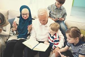 moderne muslimische großeltern mit enkelkindern, die den koran lesen foto