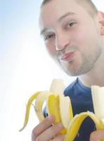 Mann, der Banane isst foto