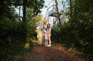 Familie mit Kindern gegen Aussichtsturm in Brünn, Tschechische Republik. Wachturm bei Sonnenuntergang mit Bäumen. foto