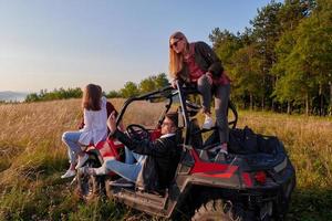 Gruppe junger glücklicher Menschen, die einen schönen sonnigen Tag genießen, während sie ein Offroad-Buggy-Auto fahren foto