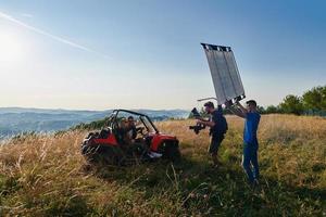 Kameramann nimmt ein junges Paar auf, das eine Buggy-Autofahrt auf einen Berg genießt foto