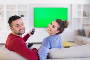 junges Paar auf dem Sofa vor dem Fernseher foto