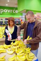 glückliches paar, das bananen kauft foto