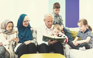 moderne muslimische großeltern mit enkelkindern, die den koran lesen foto