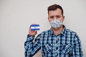 mann im karierten hemd zeigt el salvador flaggenkarte in der hand, trägt schutzmaske isoliert auf weißem hintergrund. Coronavirus-Konzept der amerikanischen Länder. foto