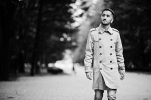 Stilvoller kuwaitischer Mann im Trenchcoat, der im Park spazieren geht. foto