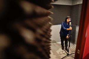 junger asiatischer sängermann mit mikrofonaufnahmelied im plattenmusikstudio. foto