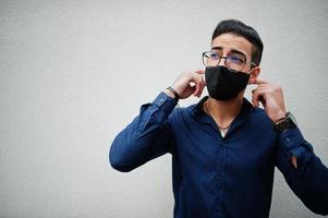 Unternehmer aus dem Nahen Osten tragen eine schwarze Gesichtsmaske und eine Brille vor einer weißen Wand. neues normales Leben nach der Coronavirus-Pandemie. foto