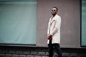 stilvoller afroamerikanischer mann trägt beige jacke mit sonnenbrille. foto